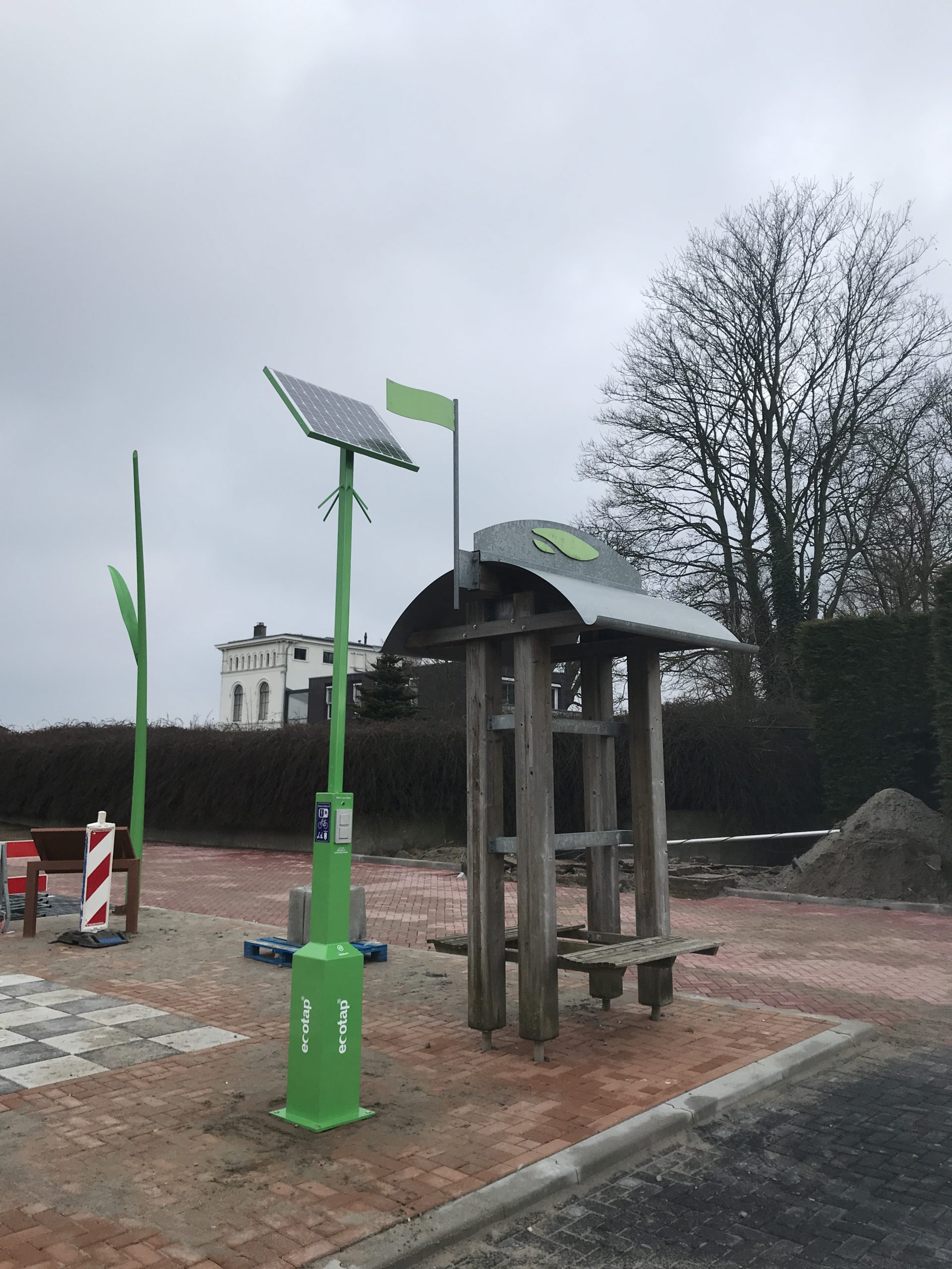 Laadpunt met windturbine en zonnepaneel in landelijke omgeving